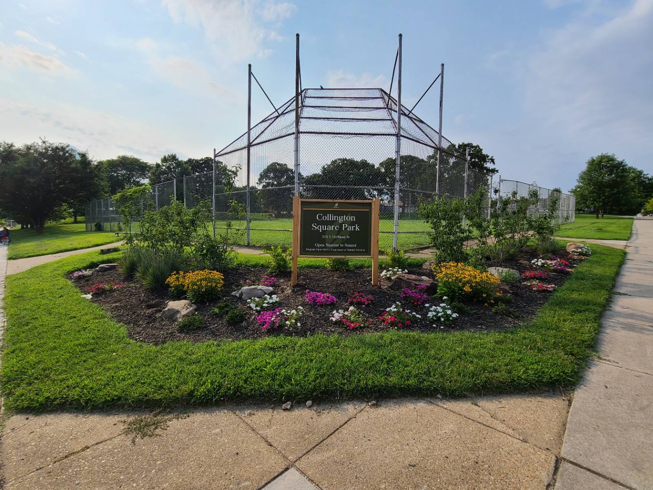 Collington Square Park entrance with flower beds and baseball field